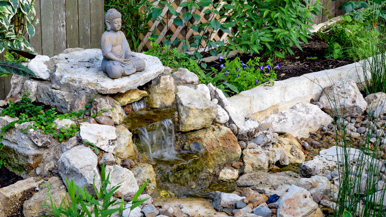 small backyard waterfall with statue