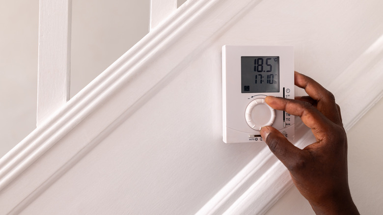 person adjusting thermostat