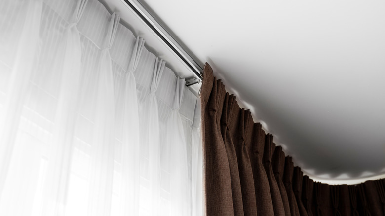 ceiling-mounted double curtain track with white linen sheer curtain hanging behind brown linen blackout curtain