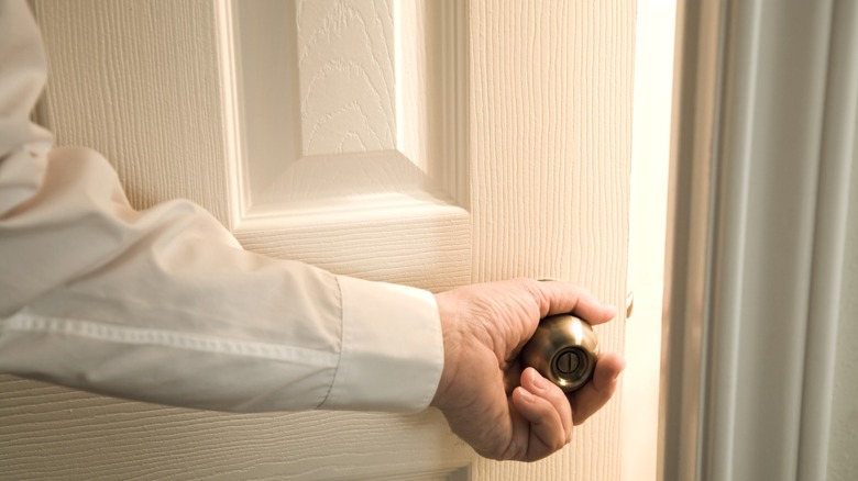 man in white shirt opening interior door