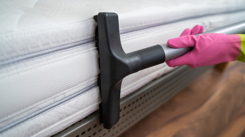 person vacuuming side of mattress