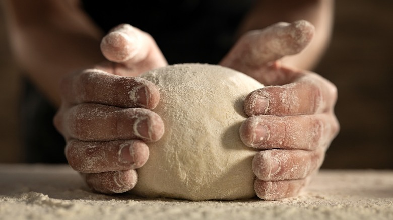 Two hands holding dough