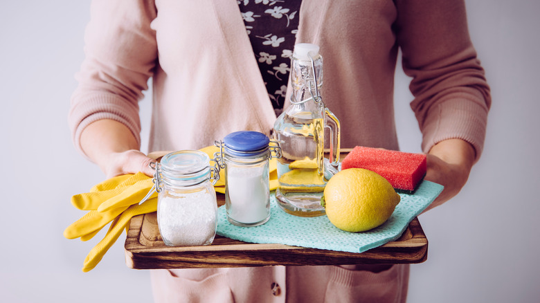 Woman holding tray of cleaning products