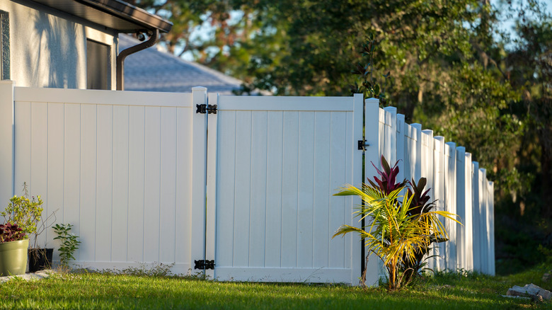 A white vinyl picket fence in front of a home