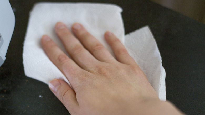 Person cleaning carpet using towel