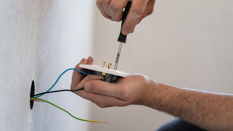 Person replacing electrical wall outlet