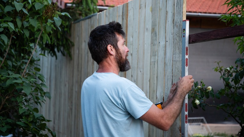 Man repairing a wood fence