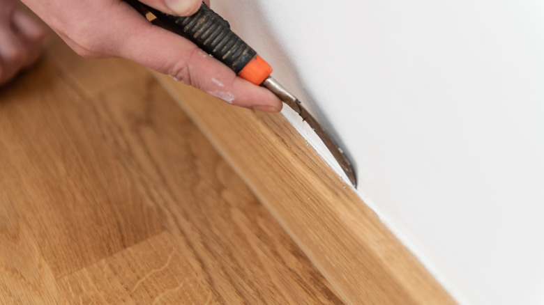 Person removing caulk with hook