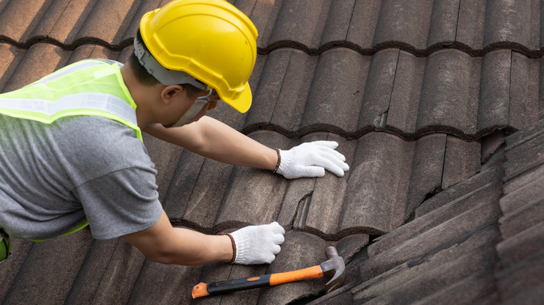 Professional roofer replacing broken tiles on a roof