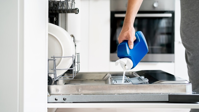 person loading liquid dishwasher soap