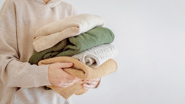 Person holding folded sweaters