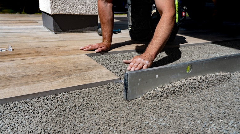 Person installing patio pavers on top of a gravel base