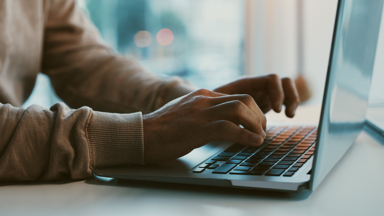 man typing on laptop keyboard