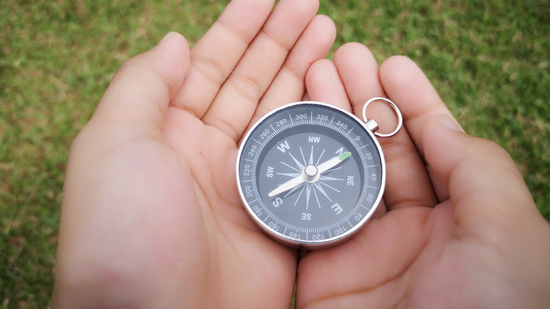 hands holding a compass outdoors