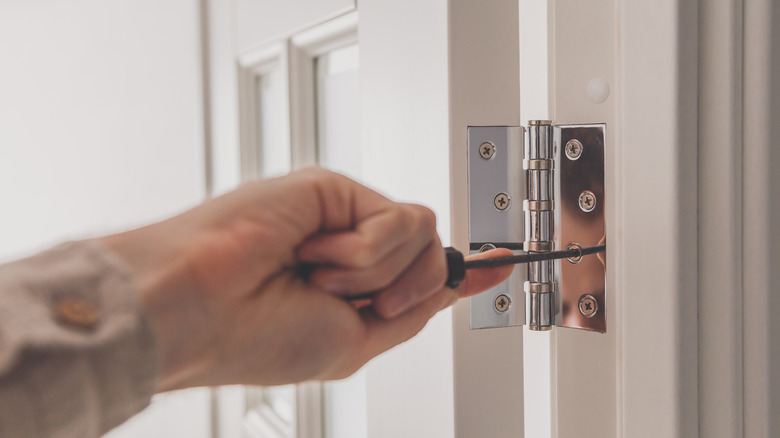 person fixing door hinge