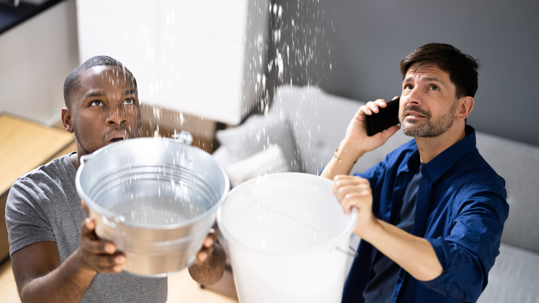 Men holding buckets under leak