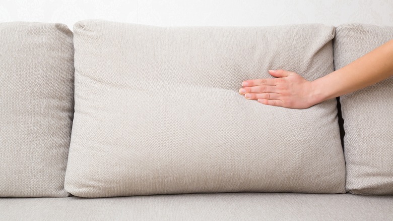 Hand pushes sofa cushion