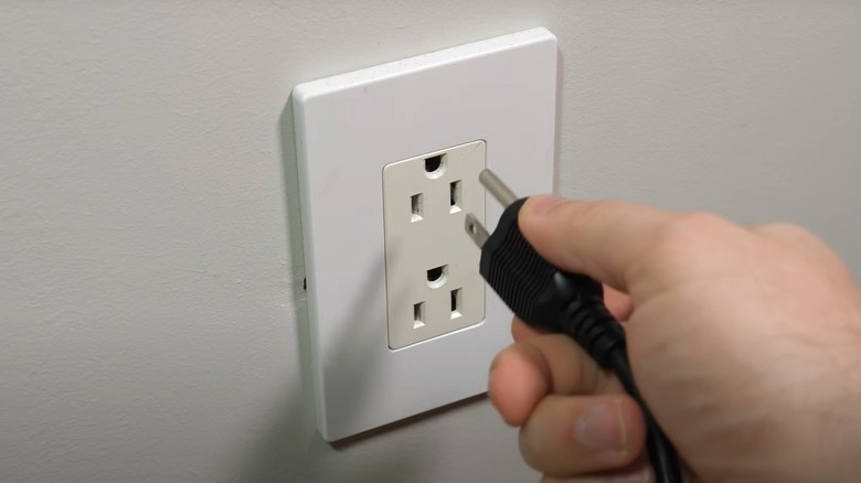 Person plugging a cord into an upside down outlet