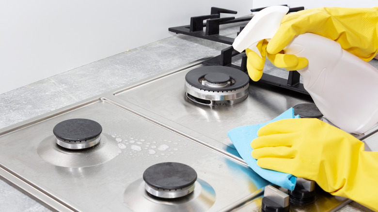 cleaning stovetop with spray bottle