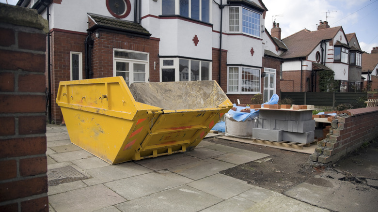 Rental dumpster near house for holding landscaping debris