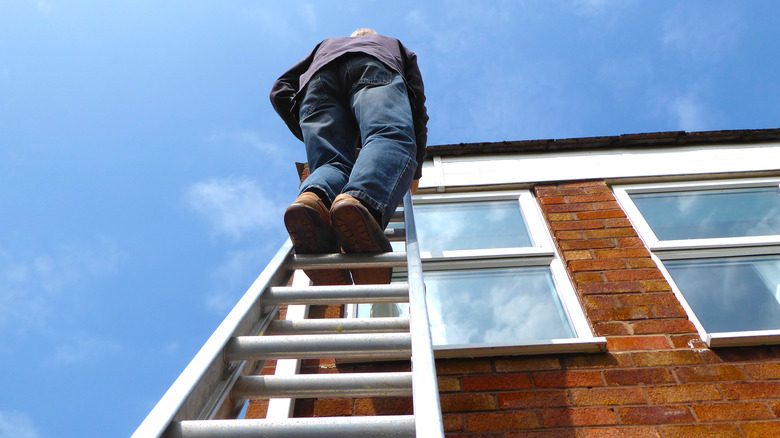 Man on ladder against house