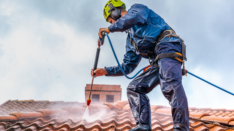 Man power washing roof