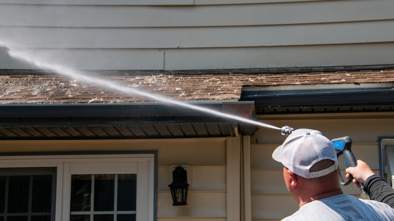 Man spraying roof with hose