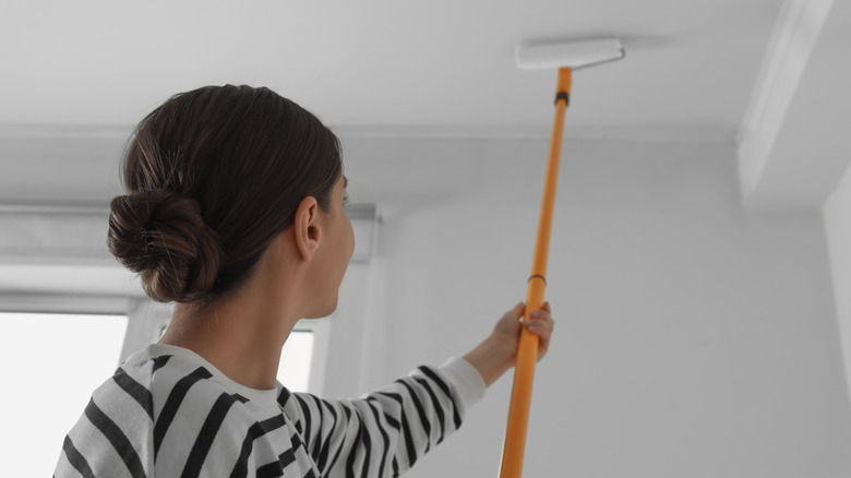 Person painting ceiling in home