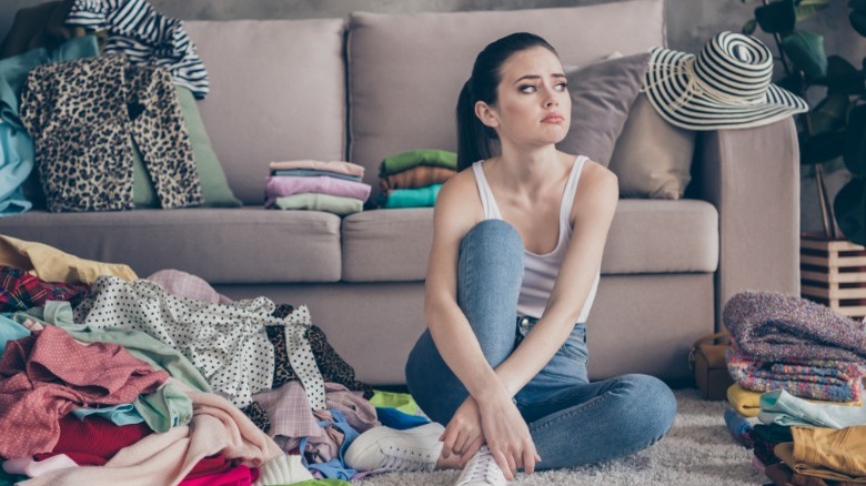 Frustrated woman in room full of clothes