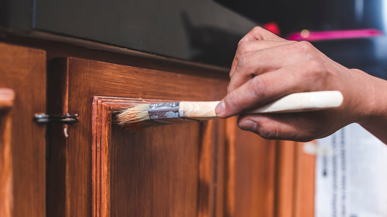 A hand applying finish to a wood cabinet