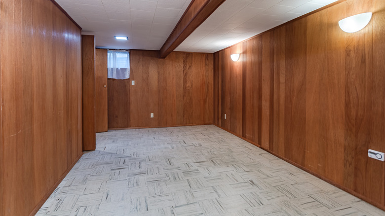 Empty room with white floors and bare wood panel walls