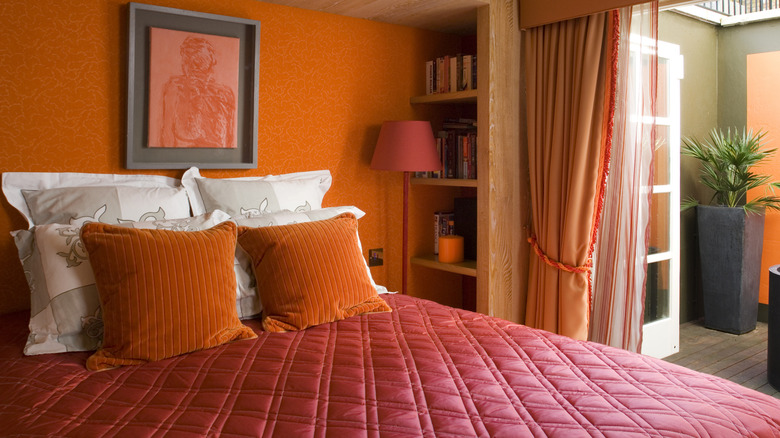 Orange bedroom with red diamond-stitch quilt on bed