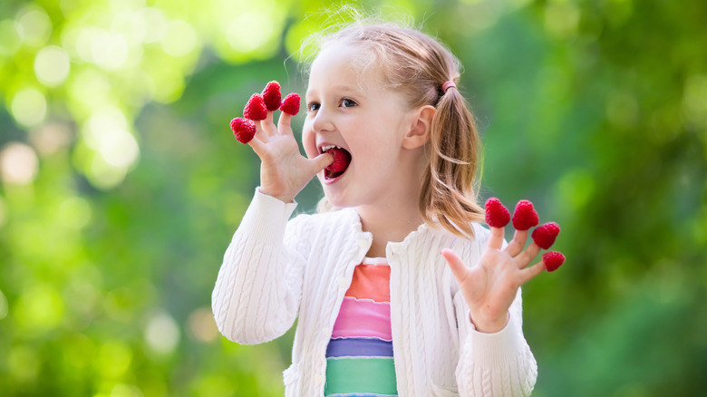 Young girl eats raspberries