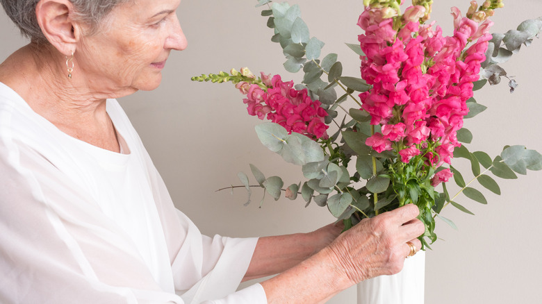 elderly woman arranging snapdragon flowers