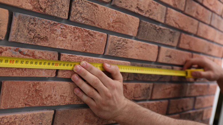 Man measuring wall with tape