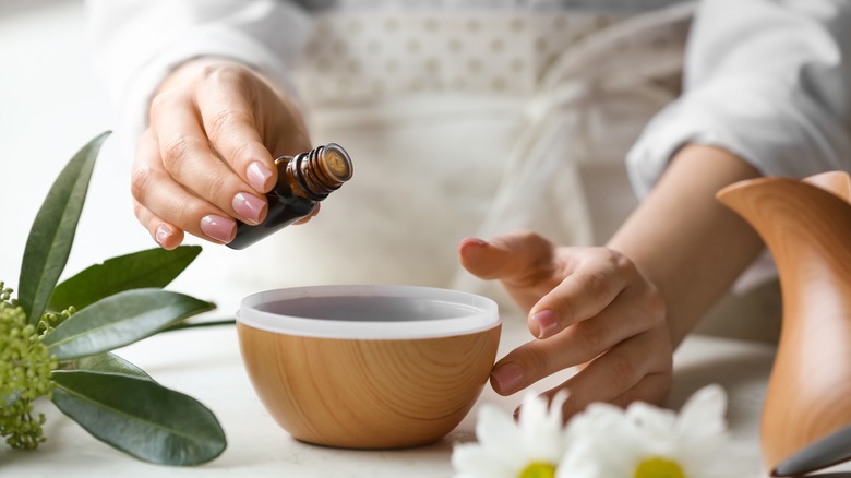 hand putting cedar oil in diffuser