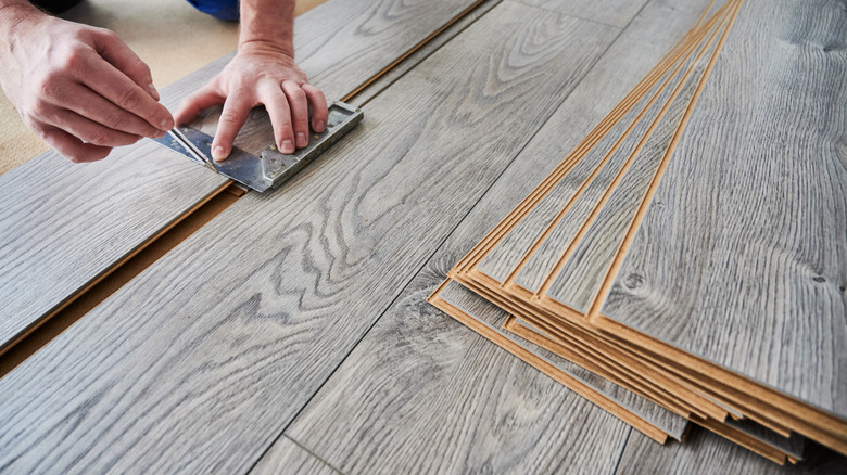 A person installs laminate flooring.