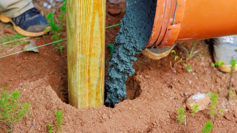 A fence post hole being filled with concrete