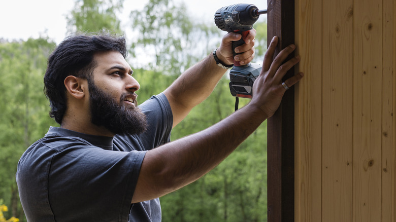 A man installing 8-foot-tall privacy fence panels