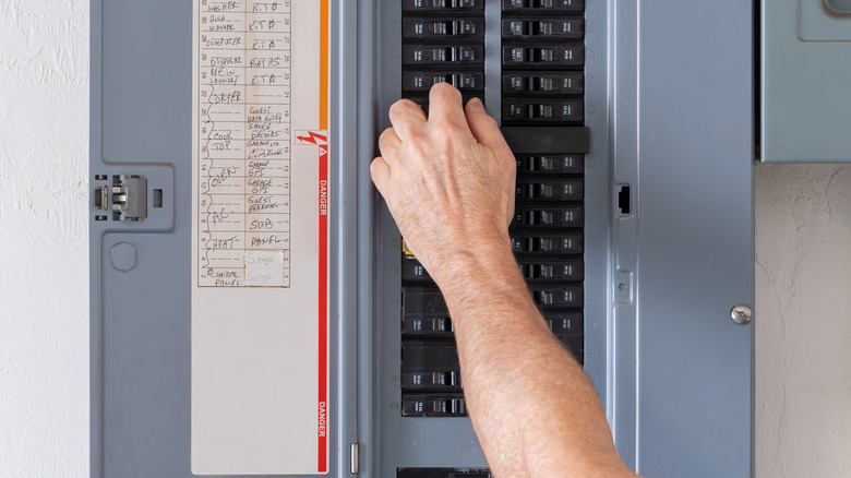 a hand flipping a circuit in a circuit box