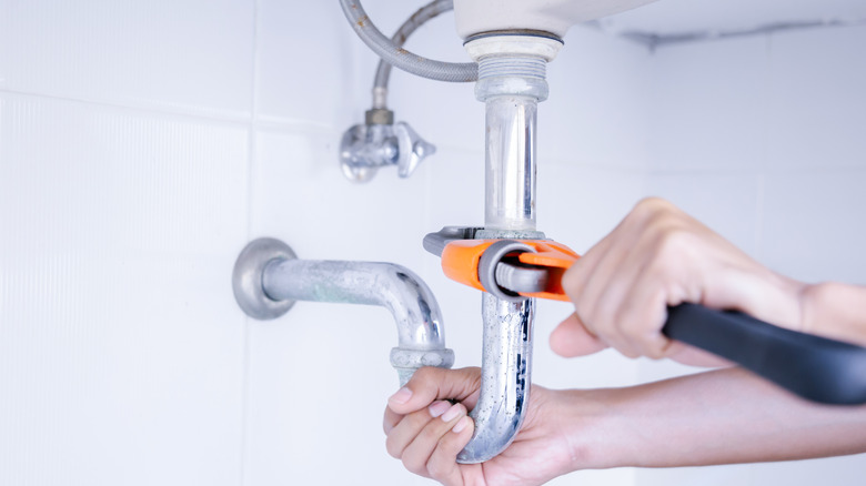 Person installing sink drain piping