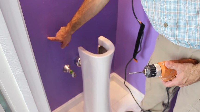 man point to drill hole on wall for sink installation