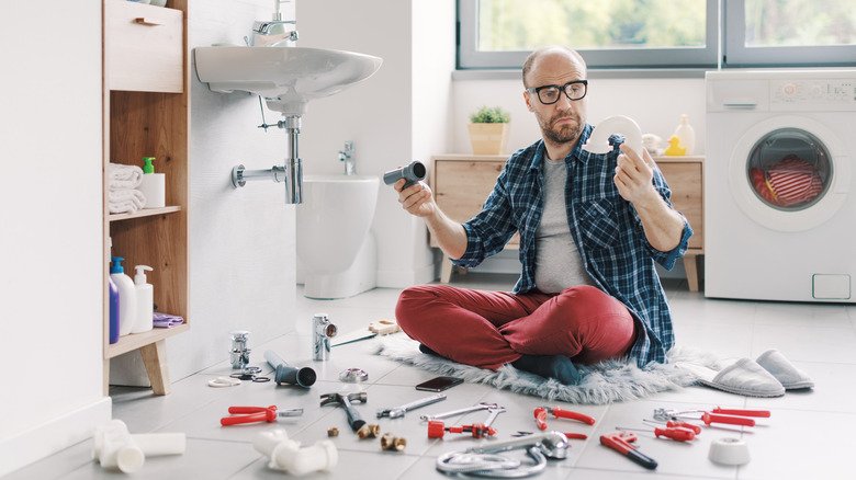 confused man staring at repair parts for bathroom sink