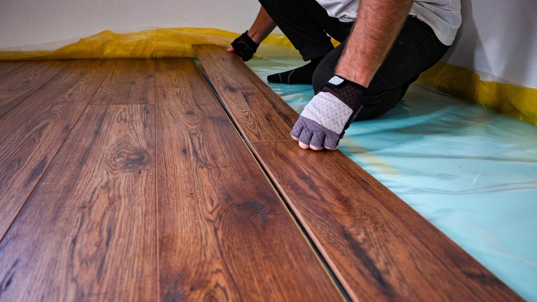 Person installing floor panels over heating system