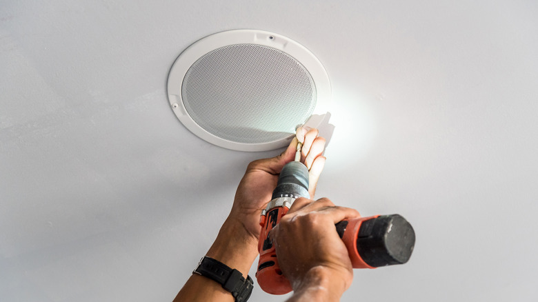 Using a drill to install in-ceiling speakers