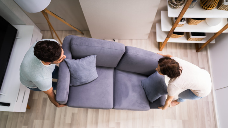 couple lifting gray couch