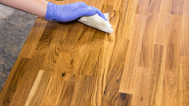 Hand wiping a butcher block surface with oil and cloth