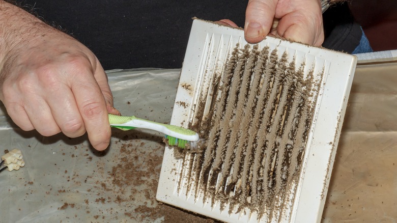 person cleaning vent fan