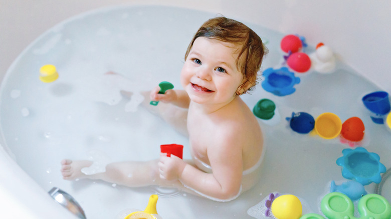 Baby in bath tub with toys 