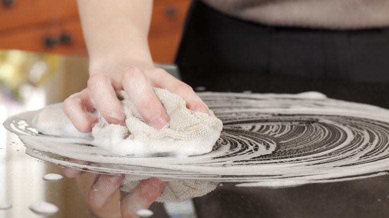 soapy cloth and hand on granite